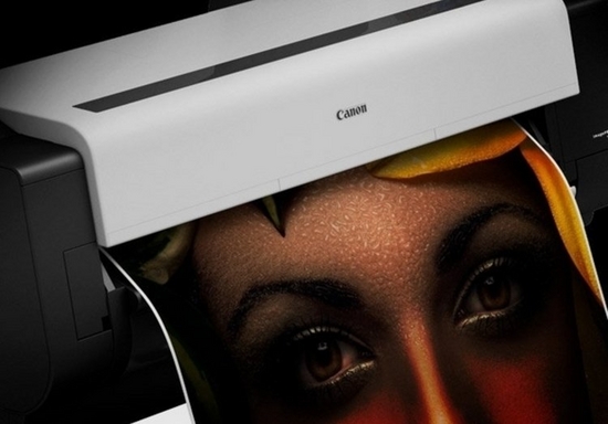 Close-up of a wide format Canon printer printing a sheet of paper with a woman’s face. 