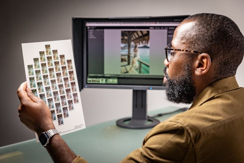 A man holds a printed sheet showing thumbnail images arranged in a diamond shape. In the background, a monitor displays the same image at full-screen size.