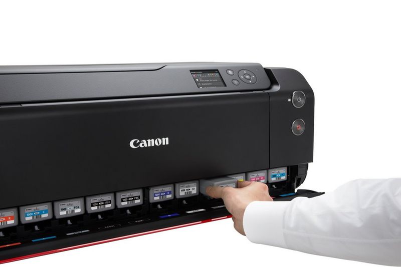 Un uomo cambia con una mano uno dei 12 serbatoi d'inchiostro nella parte anteriore di una stampante Canon imagePROGRAF PRO-1000.