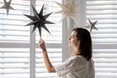 A woman poses for a portrait, sitting next to a window, in-between a reflector and plant.