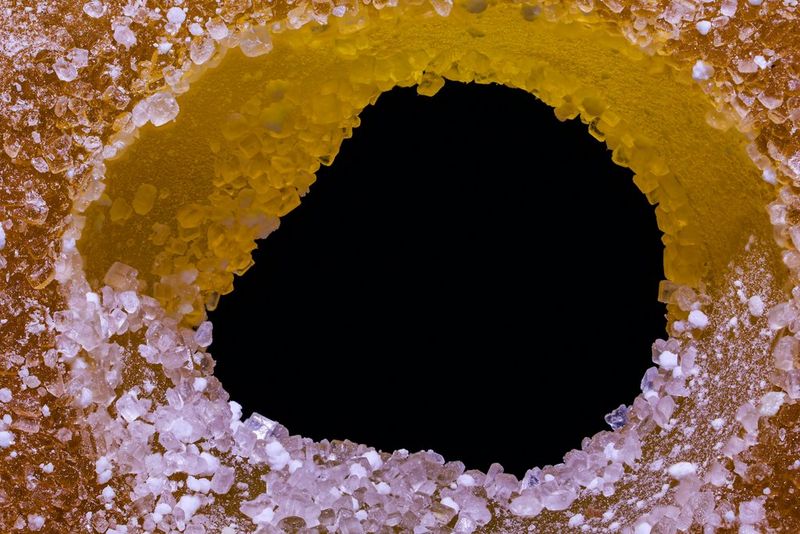 Cukura figūriņas makro tuvplāns, kas apgaismots tā, lai caurums vidū izskatītos melns; uzņemts ar Canon EOS R10 un Canon RF 100mm F2.8L MACRO IS USM objektīvu.
