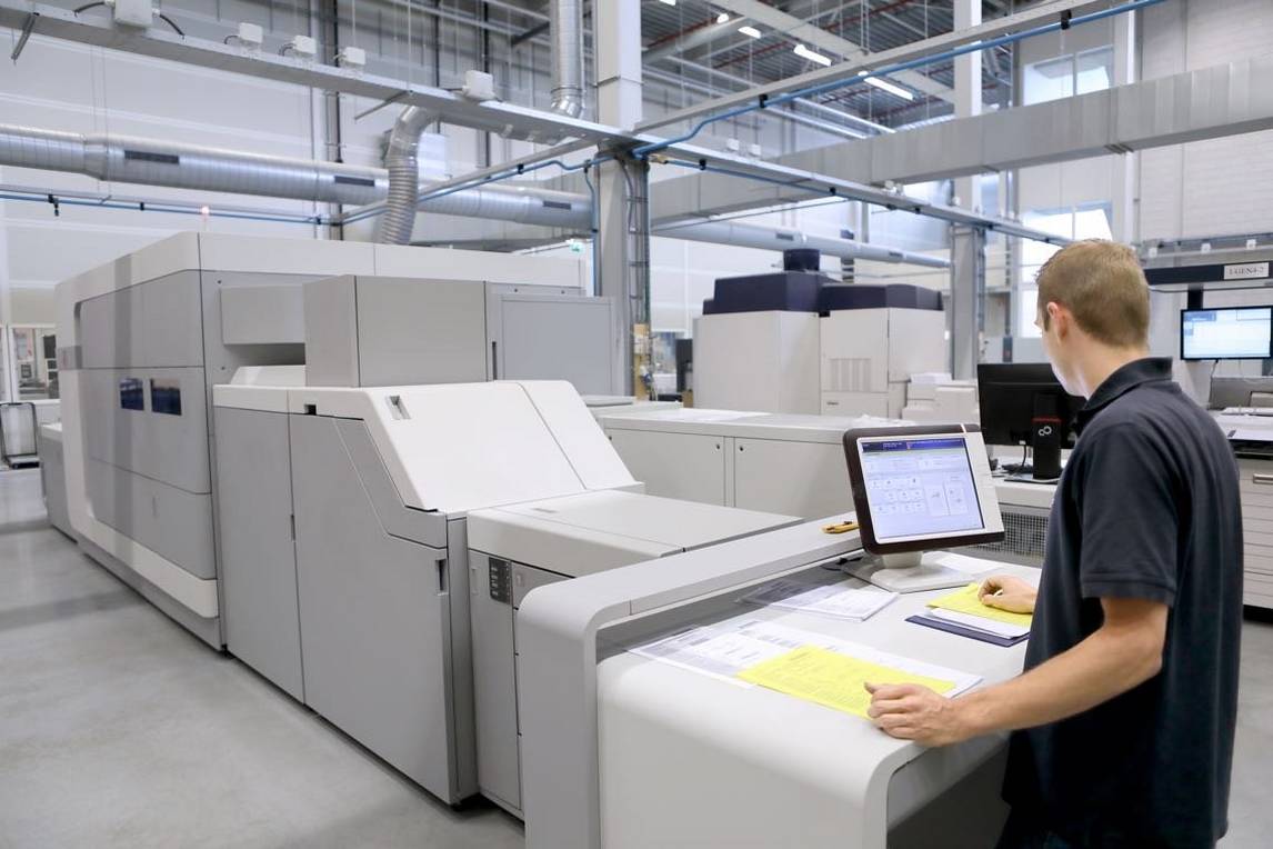 Man works at computer in front of high speed inkjet press