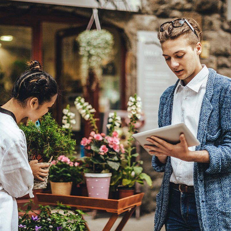 man looking at tablet while shopping at a florist