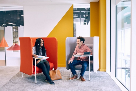 Woman and man sit in their orange and grey chair chatting