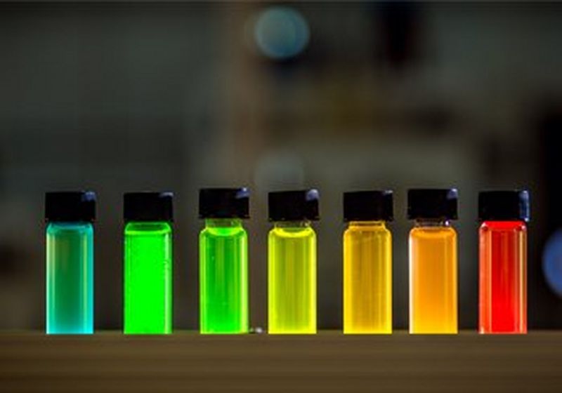 A row of black-capped vials containing fluorescent liquids.