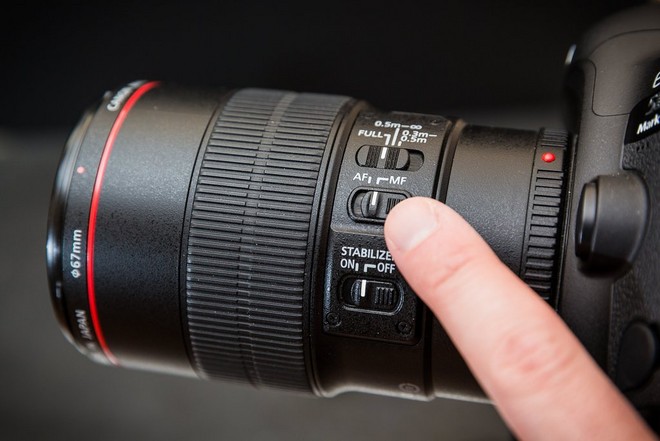 Палец пользователя указывает на переключатель AF/MF на оправе объектива Canon.