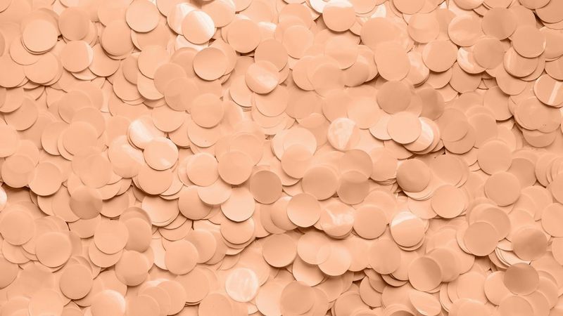 Thousands of circles of shiny peach confetti covering the entire image.
