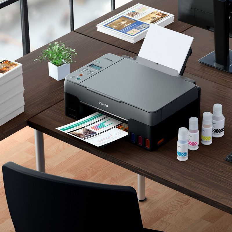 PIXMA G3560 mit Fotodrucken und kompatiblen Tinten auf einem Schreibtisch