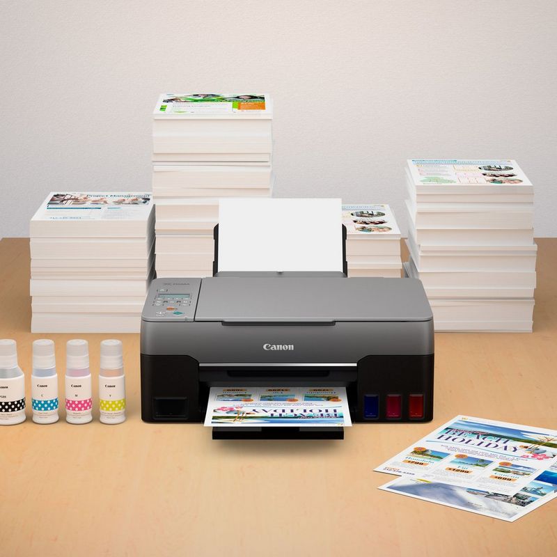 PIXMA G3560 mit einem Stapel von Fotodrucken und kompatiblen Tinten auf einem Schreibtisch