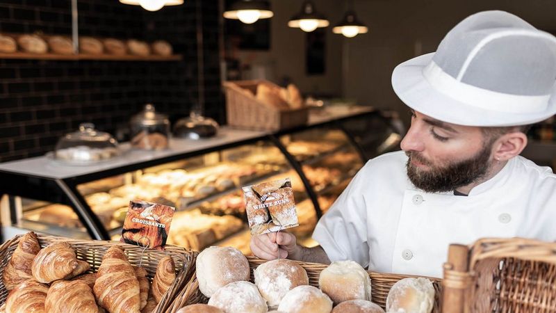 Man at bakery stall surrounded by pastries in basket
