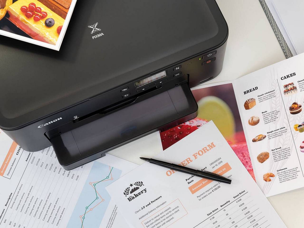 Top view of Canon PIXMA Black Printer surrounded by prints