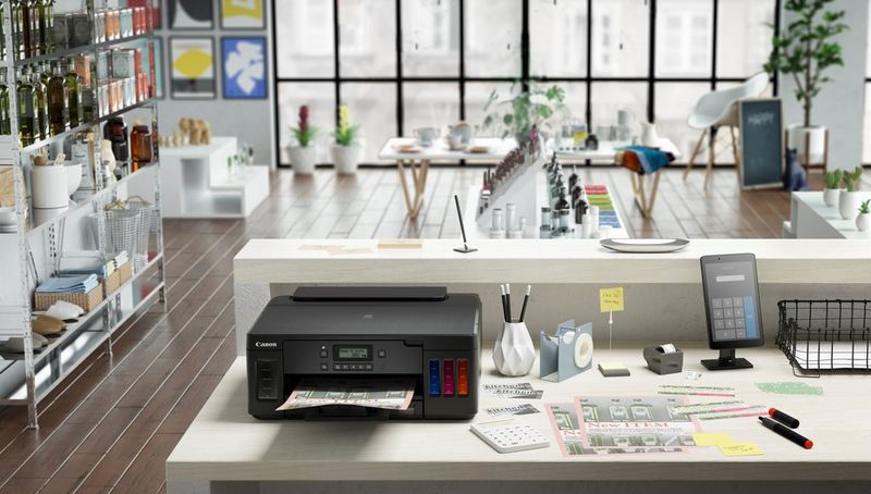 A Canon PIXMA printer on a desk in an office setting.