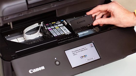 A Canon printer with the ink cartridge being inserted.