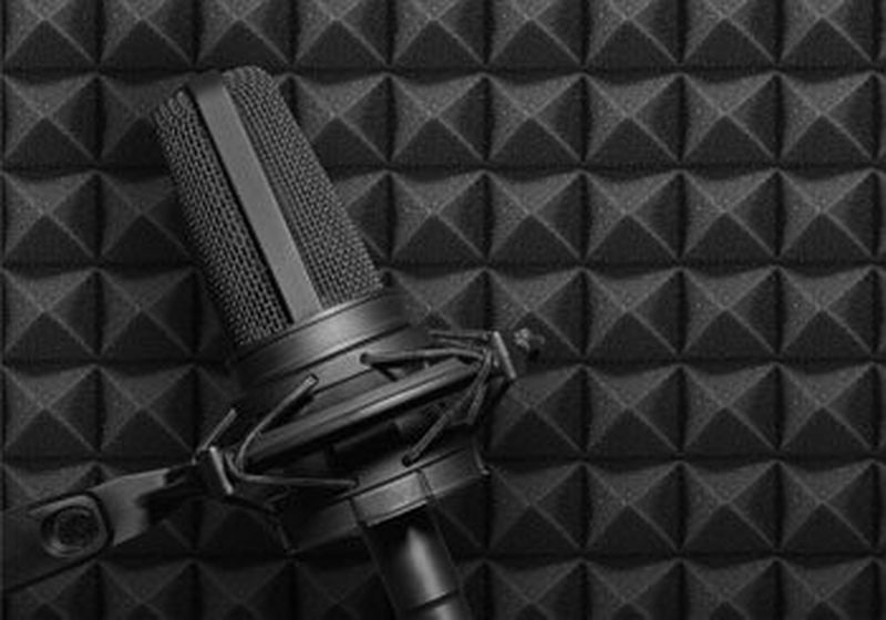 A recording studio microphone on black acoustic foam background.