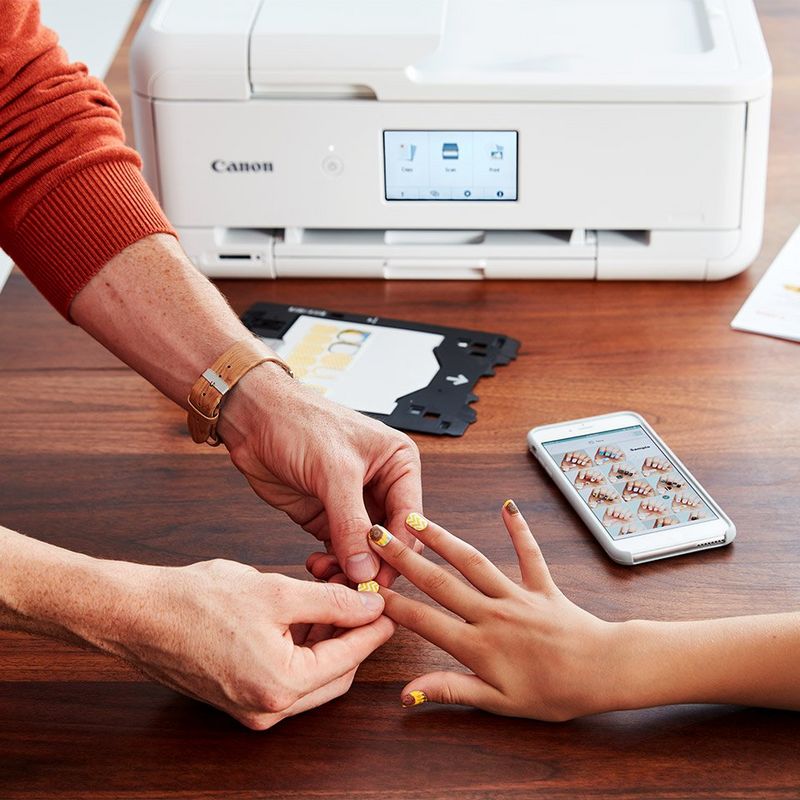 Father helping daughter apply nail stickers printed on the Canon PIXMA TS9550