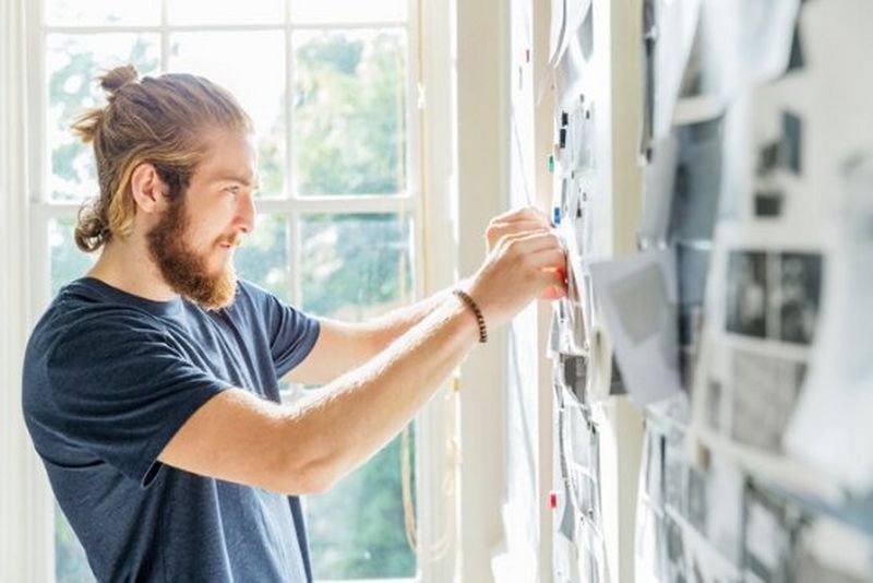 Man pinning print onto wall