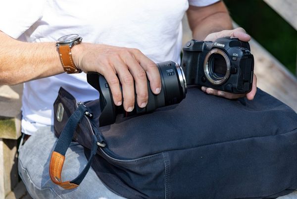 A man prepares to attach a lens to the Canon EOS R5 camera.