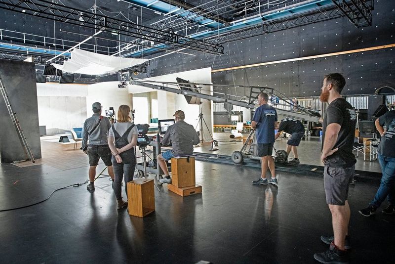 Crew gathered around as filming starts on a furniture set for an advertisement.
