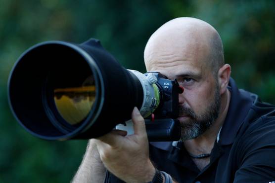 Richard Heathcote looks through the viewfinder of a Canon 中国福彩网5 camera with telephoto lens attached.