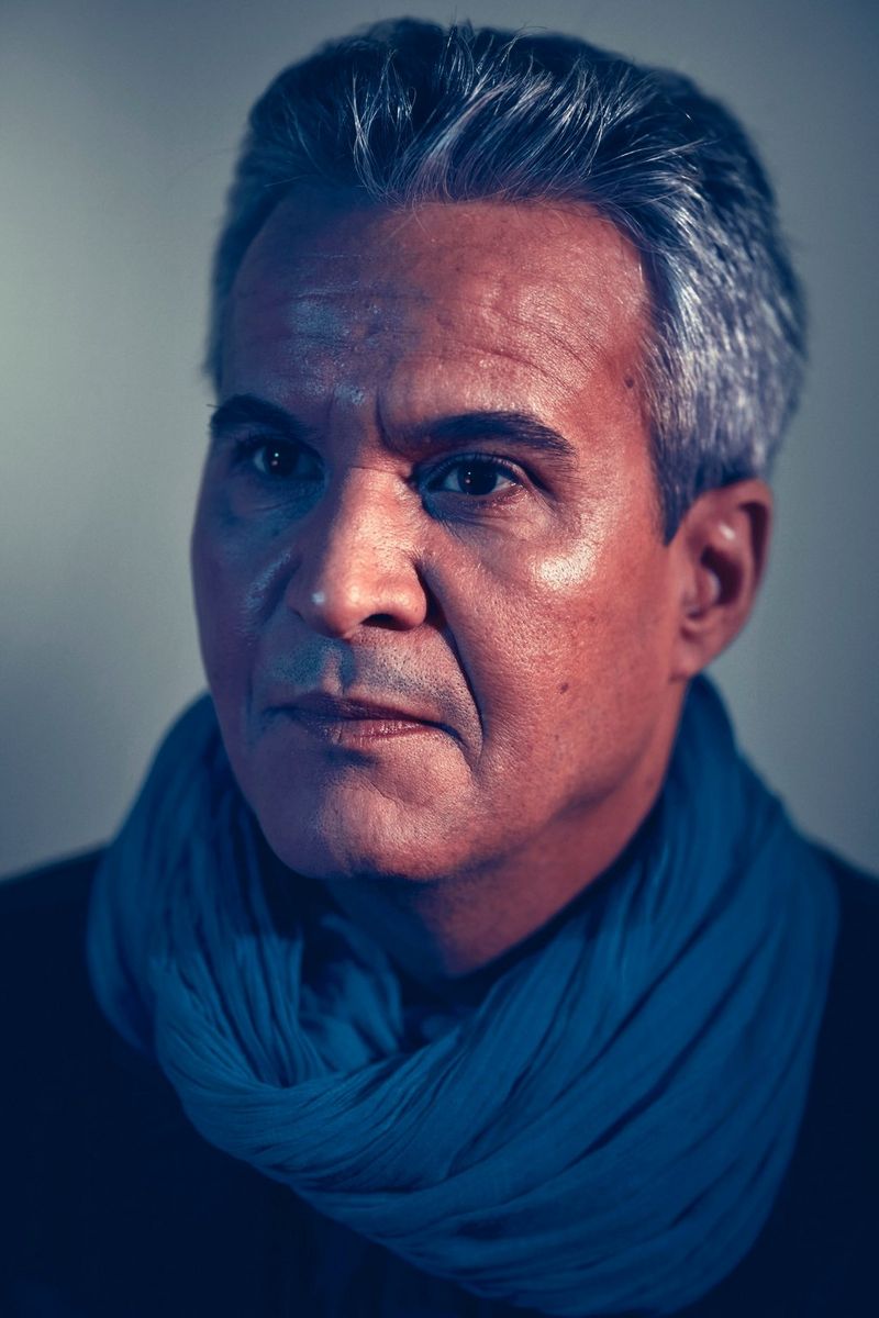 Portrait d'un homme aux cheveux gris portant un foulard bleu.