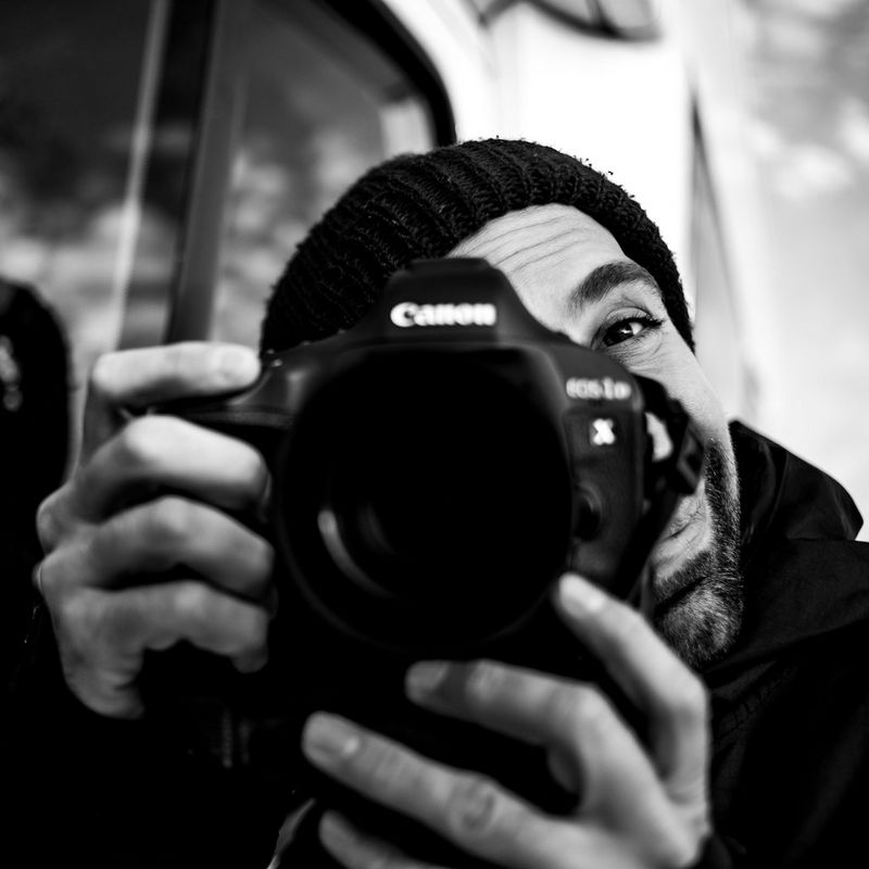 A black and white headshot of Canon Ambassador Alexandros Grymanis holding a Canon camera.
