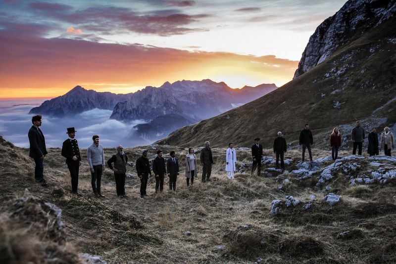 Several people form a human chain on a hillside at sunset, snow-capped mountains under orange clouds in the background. Taken on a Canon EOS-1D X by Canon Ambassador Aljoša Rebolj.