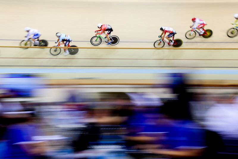 Dans un vélodrome en Biélorussie, les cyclistes passent en trombe devant l'objectif, faisant apparaître le public flou.