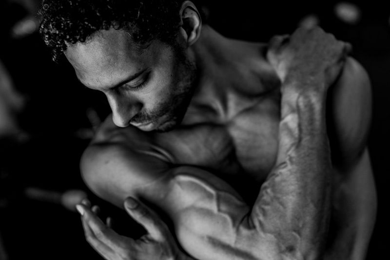 Gros plan sur la tête et le torse d'un homme enroulant ses bras autour de son corps.