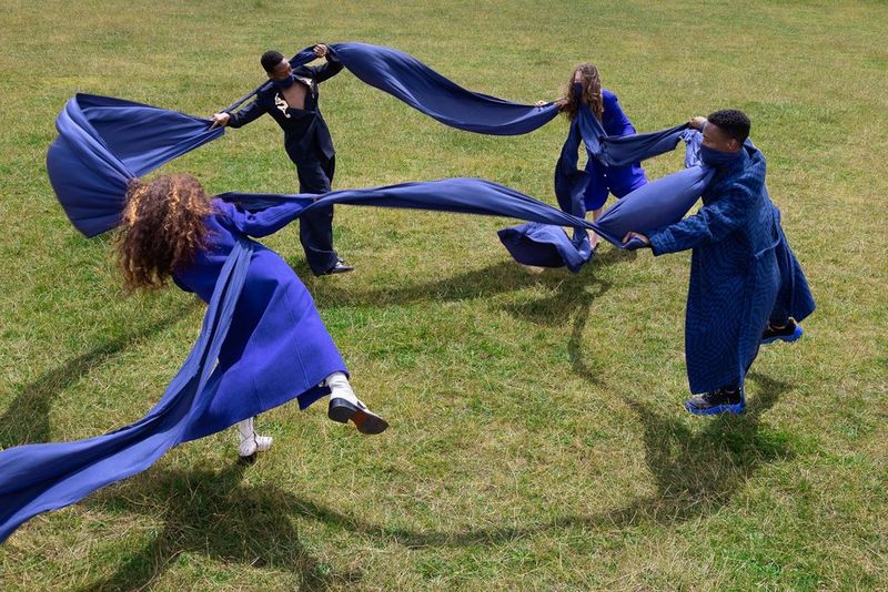 Un cercle de danseurs reliés par une longue écharpe en soie bleue qui s'enroule autour de leurs visages.