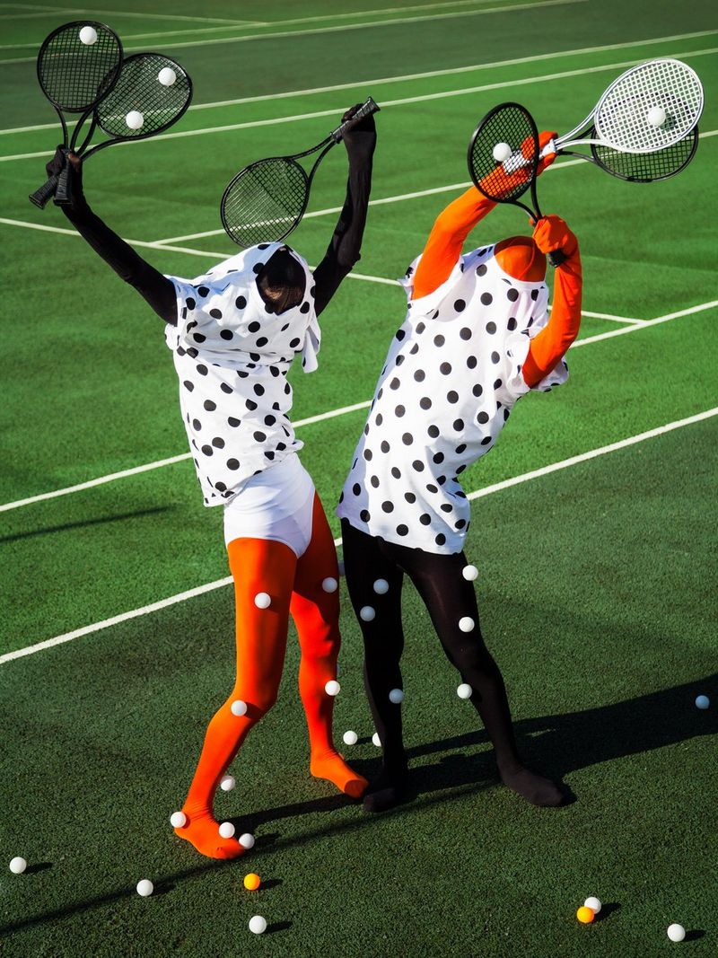 Deux mannequins en collants et hauts à pois et aux visages masqués tiennent des raquettes de tennis en l'air.