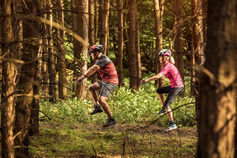Deux cyclistes semblent assis sur des vélos invisibles dans la forêt