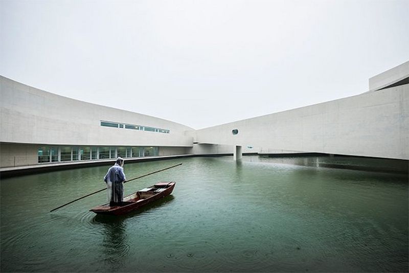 Un homme portant un équipement de protection navigue une barque sur l'eau entre les structures de béton de l'usine chimique Shihlien de Huai'an, en Chine.