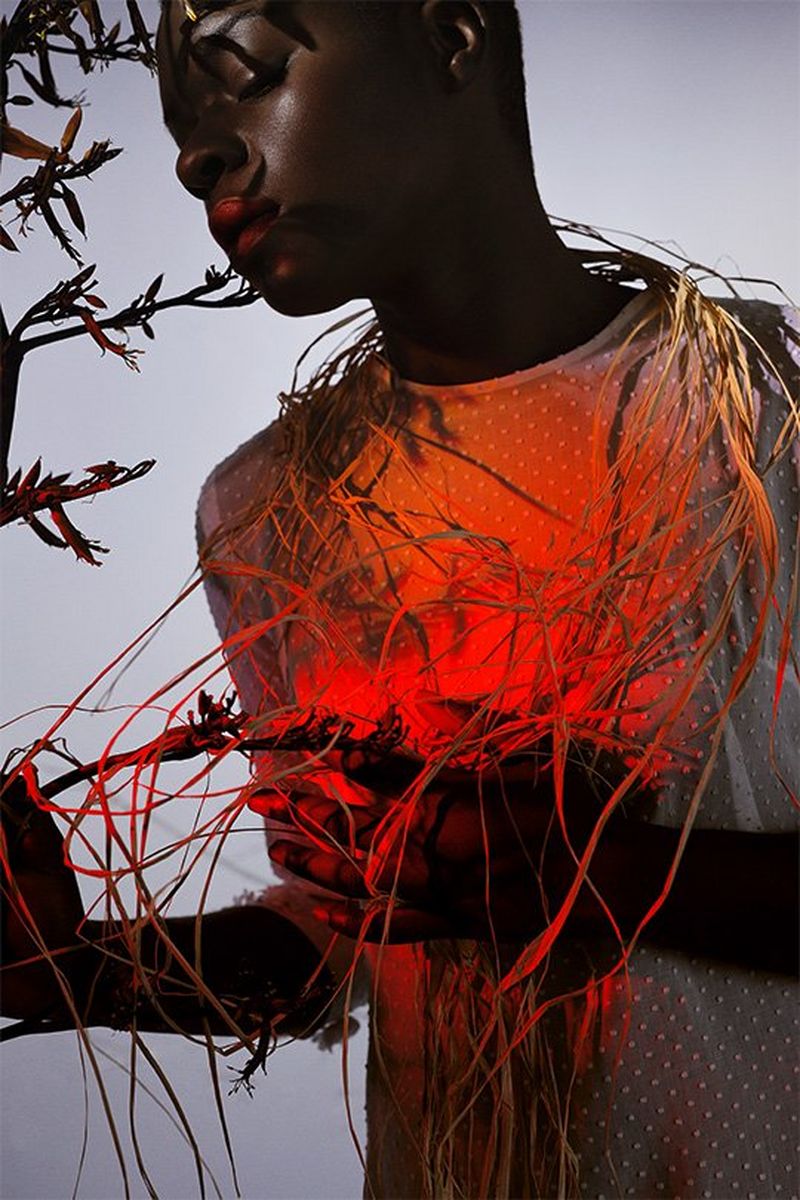 Un mannequin est éclairé avec une lumière rouge et enveloppé avec des lianes.