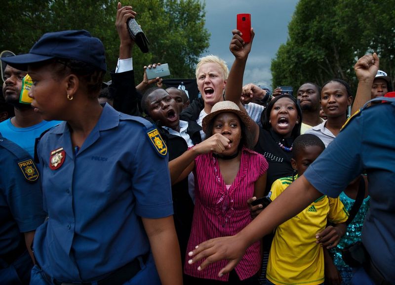 La police sud-africaine retient une foule hurlante.