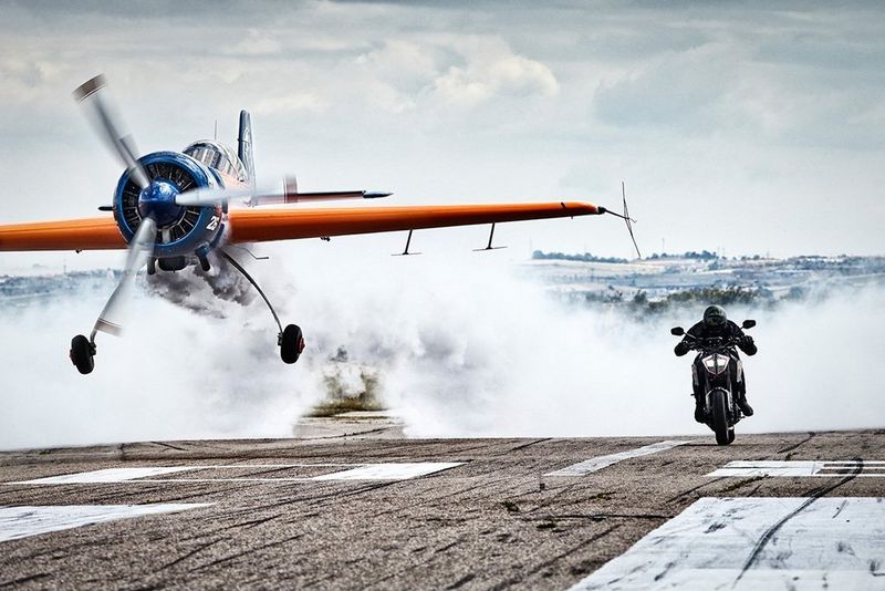Un avion de voltige et une moto font la course et se dirigent vers l'appareil photo sur une piste à Casarrubios, en Espagne.