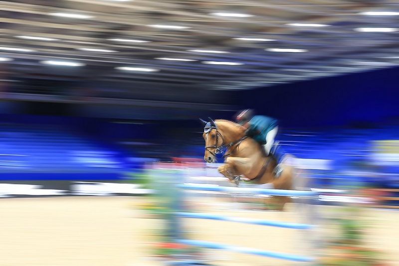 Une photo d'un sauteur d'obstacles prise avec une longue exposition pour créer des stries de couleur sur l'image.