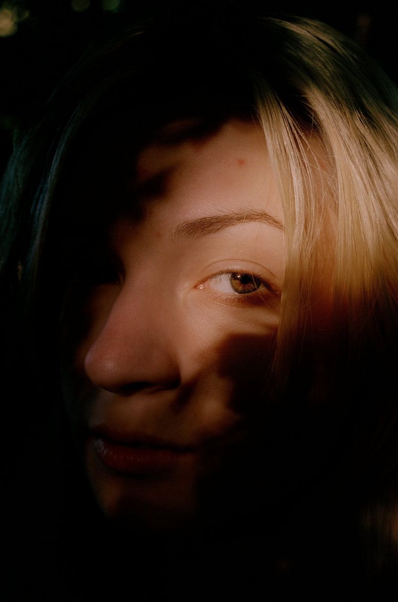 Portrait d'une jeune fille, la majeure partie de son visage dans l'ombre.