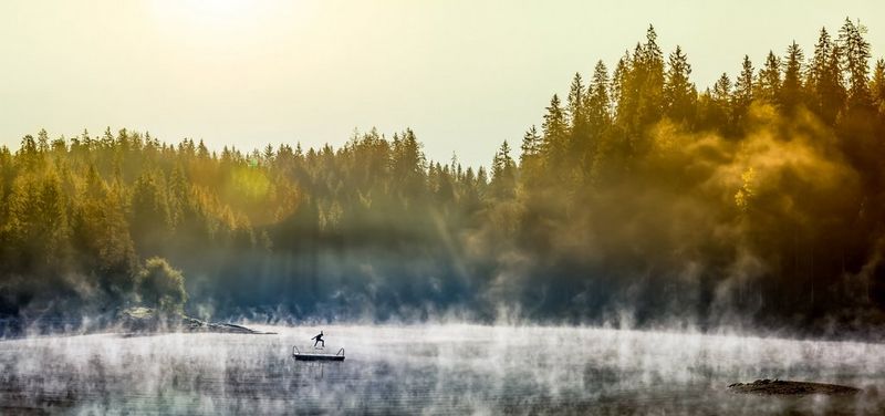 Au loin, un skateboarder s'entraîne à réaliser des figures sur une plateforme au centre d'un lac. La brume matinale se lève et l'enveloppe.
