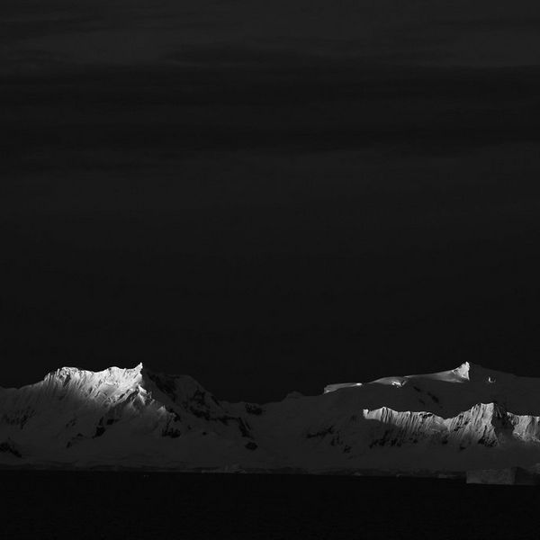 The last of the midnight sun spills over mountain ridges in Antarctica.