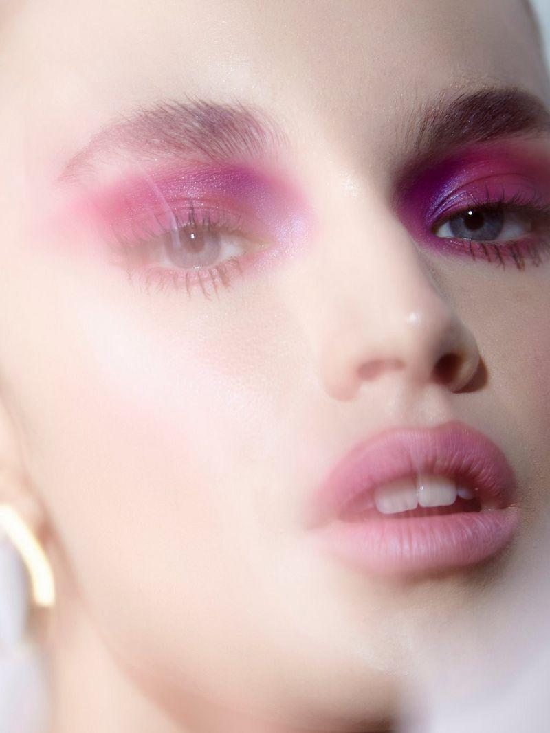 Une image en gros plan d'une mannequin portant du fard à paupières rose vif et du rouge à lèvres.