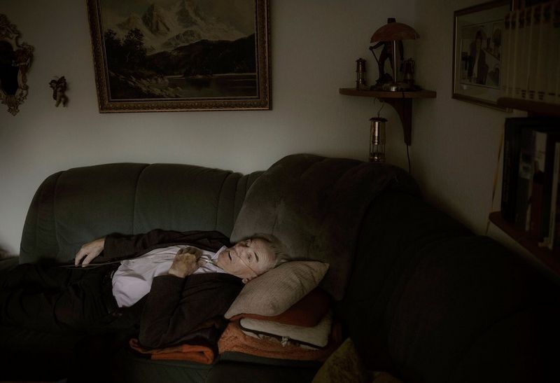 Un homme âgé équipé d'une aide respiratoire est allongé sur un canapé.