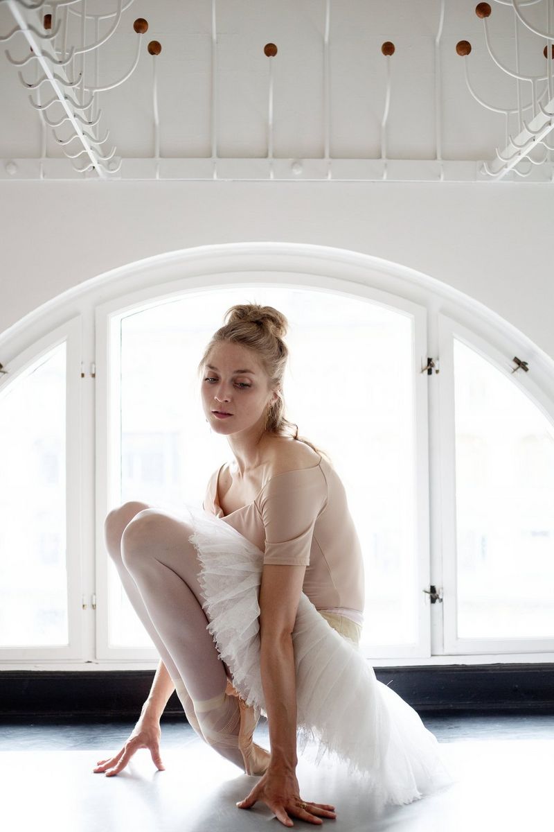 Une ballerine sur pointe s'accroupit pour s'étirer avant une représentation.