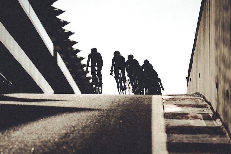 Un groupe de silhouettes de cyclistes atteignant le sommet d'une montagne.
