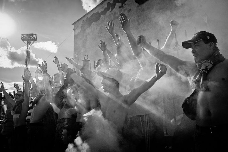 Des supporters de football russes, torse nu et les bras en l'air, entourés par de la fumée de fumigènes.