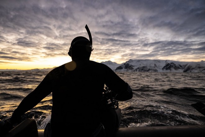La silhouette di Stéphane Granzotto, con muta e boccaglio, mentre si prepara a tuffarsi nell'Oceano Artico.
