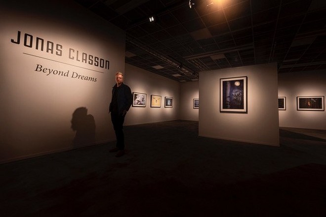 Il fotografo Jonas Classon si trova in una sala espositiva accanto a Night Hunter, la sua pluripremiata fotografia di un grande gufo grigio.