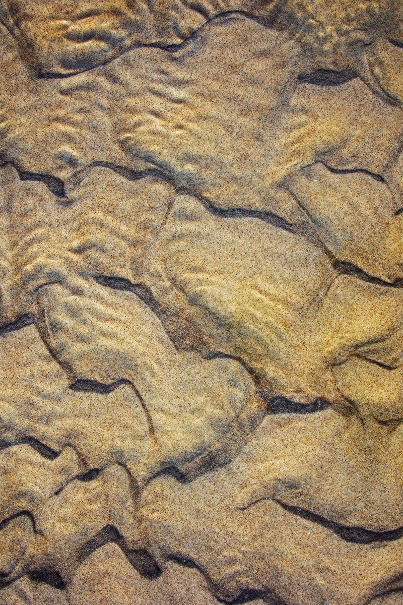 Gros-plan sur différentes textures du lit d'une rivière, qui ressemblent à un paysage aérien.