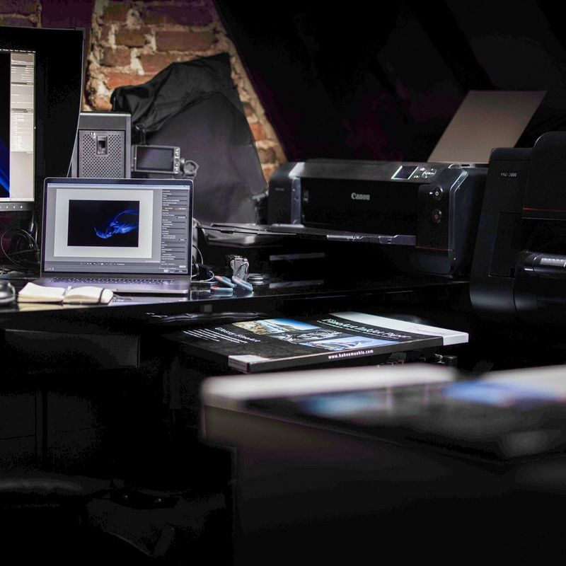 A professional home photography studio containing a laptop, the edge of a large screen and a Canon printer. 