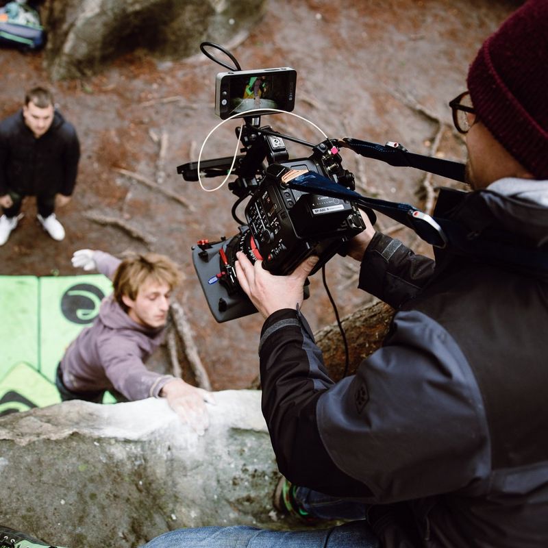 Le réalisateur Nicolai Deutsch est agenouillé sur le bord d'une corniche pour réaliser une prise de vue en plongée de deux alpinistes avec une Canon EOS C500 Mark II.