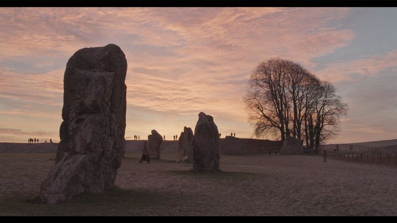 一部电影仍然显示田野里的四块大石头，太阳从后面升起。
